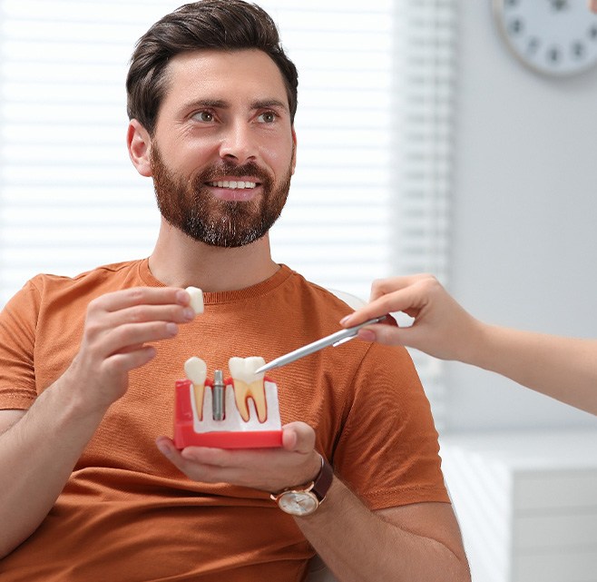 a patient holding a dental implant model