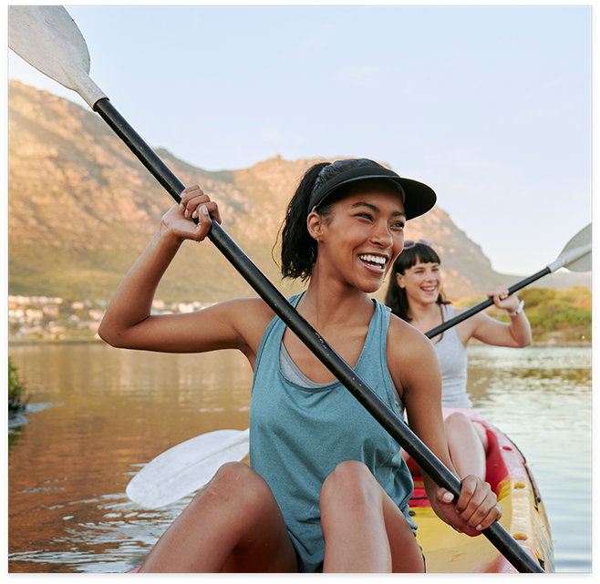 Two women paddling down river in canoe