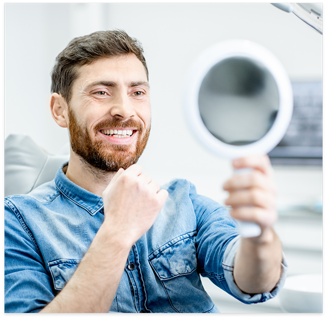 Man in dental chair checking smile in mirror