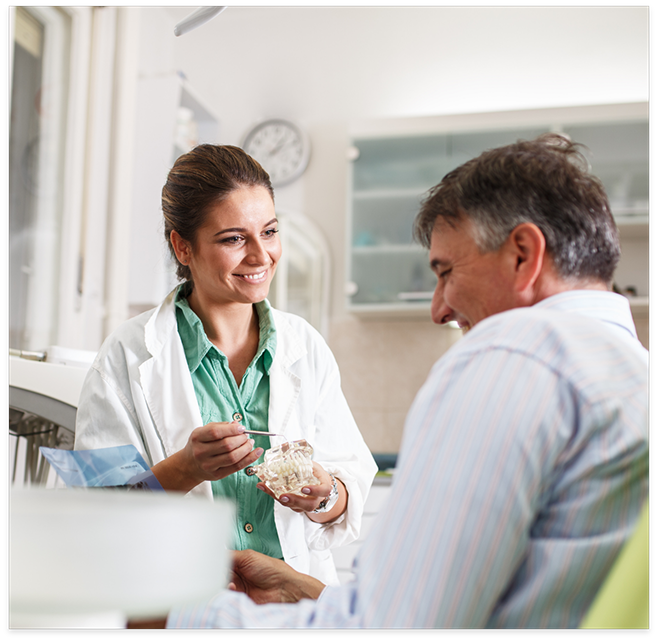 Female dentist showing male patient model of dental implants