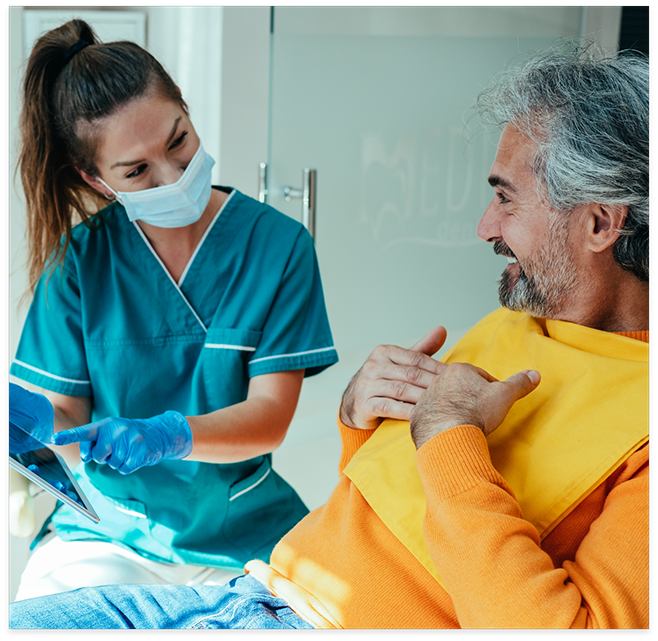 Female dentist talking to male patient in yellow shirt