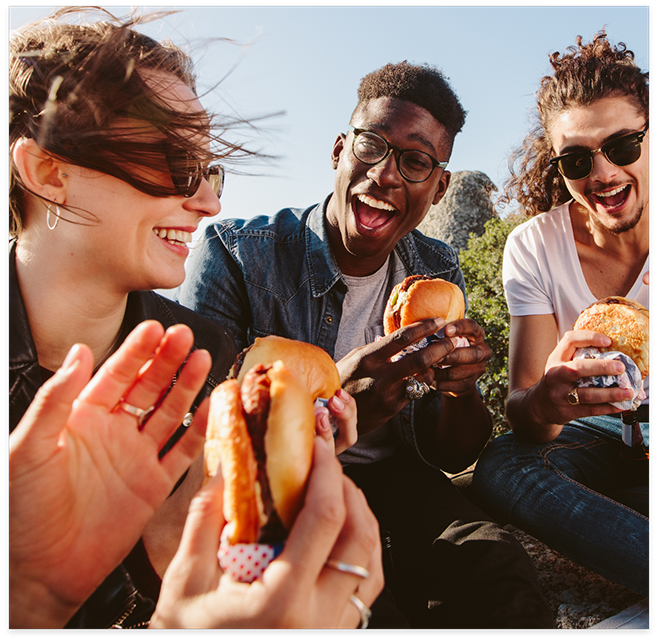 People sitting in a circle outside eating sandwiches