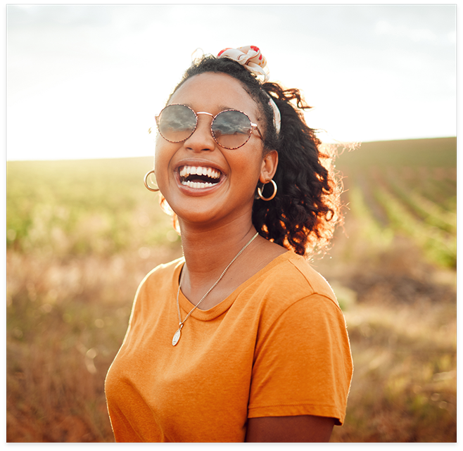 Woman with orange shirt smiling in field