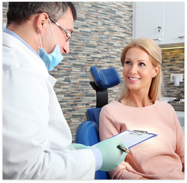 Dentist talking to female patient wearing pink shirt