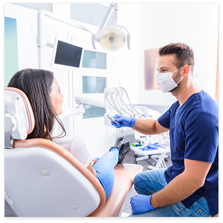 Dentist with mask speaking to female dental patient