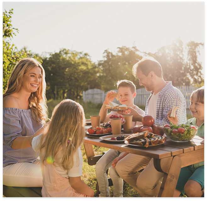 Entire family eating at a picnic table on sunny day