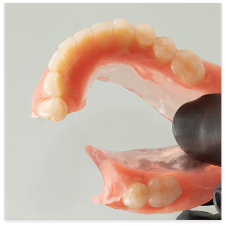 Gloved hand holding a broken denture