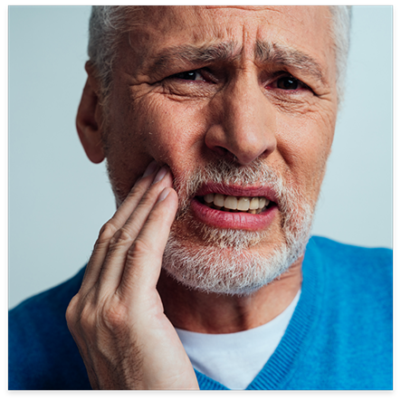 Bearded man rubbing jaw in pain