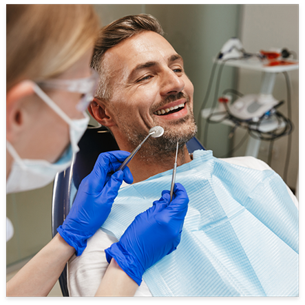 Man in dental chair and dentist holding dental instruments