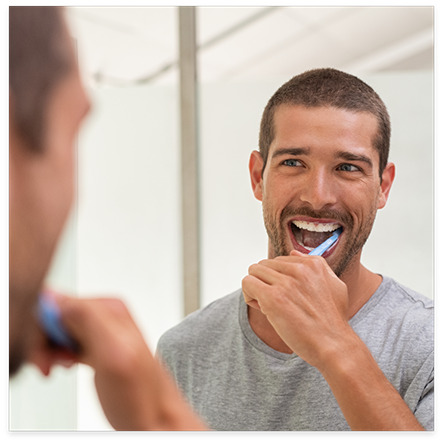 Man brushing his teeth in mirror