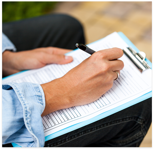 Close up of patient completing form on clipboard