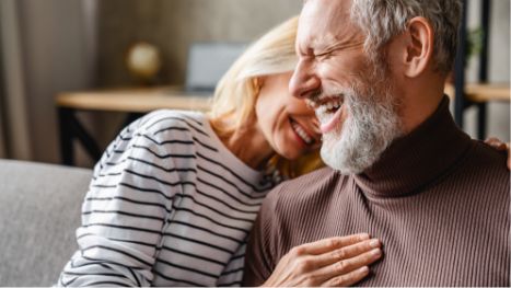 Senior couple sitting on couch and smiling