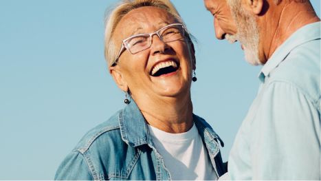 Senior man and woman laughing outside together