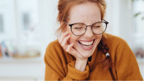 Woman with orange shirt and glasses smiling