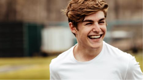 Man in white shirt smiling outside