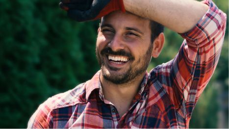 Man in flannel shirt smiling outside