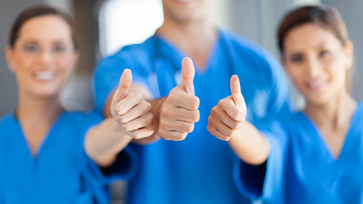 Three dental team members giving thumbs up