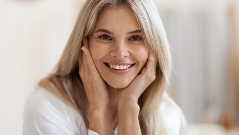 Blonde woman smiling with hands on face