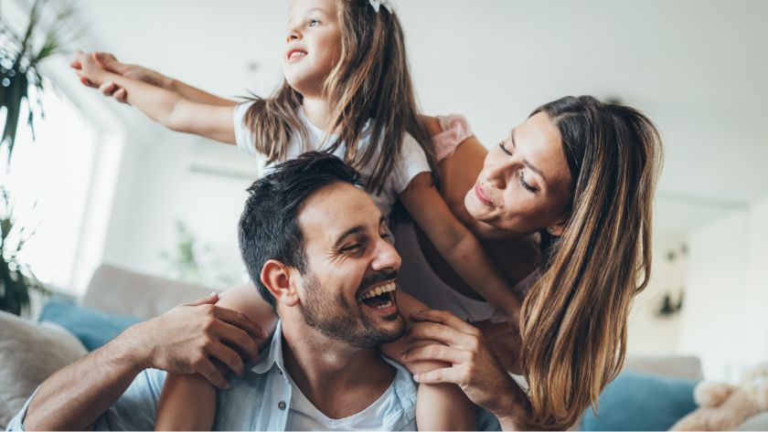 Man carrying daughter with wife behind them