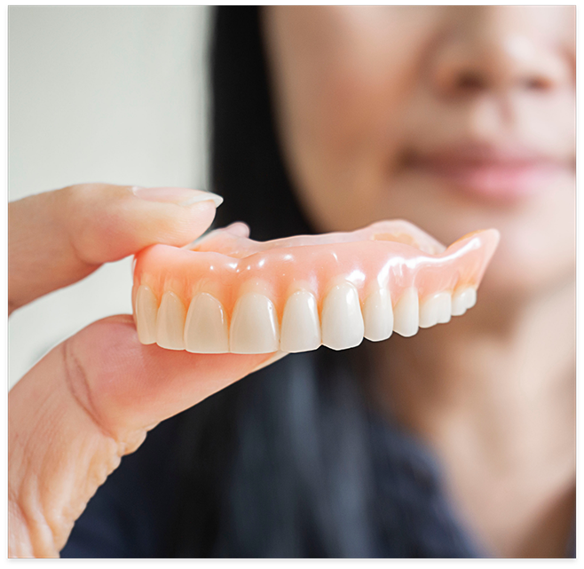 Close up of woman holding a denture