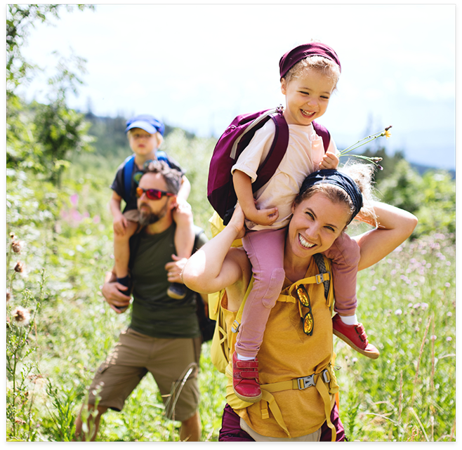 Parents giving kids piggyback rides while hiking