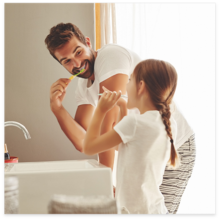 Man and daughter brushing their teeth together