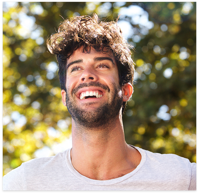 Man with beard standing in front of trees smiling