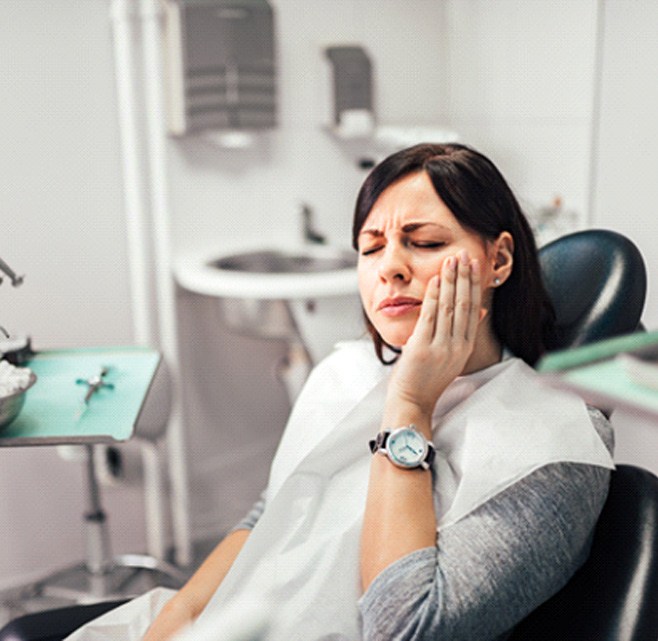 Woman with toothache sitting in treatment chair