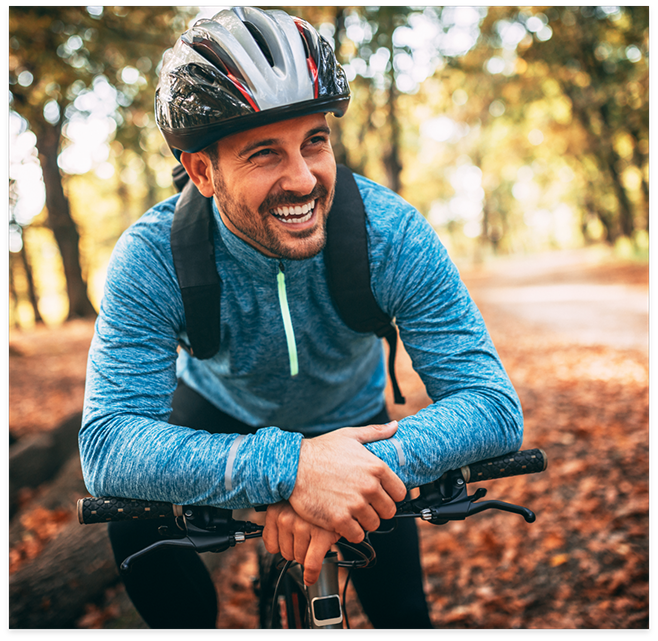 Man smiling while cycling through the woods