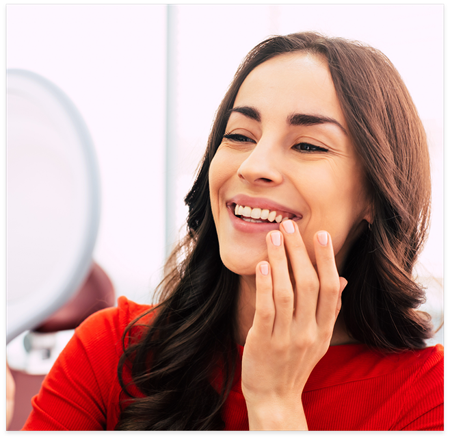 Female patient in red shirt checking teeth in mirror