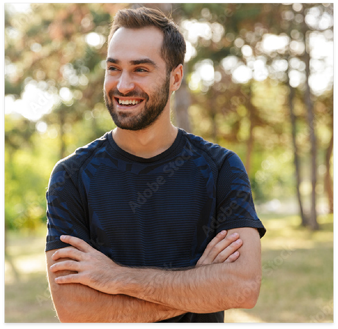 Man in woods smiling with arms folded