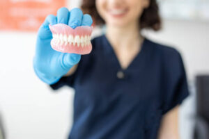 Dental lab technician holding a pair of dentures