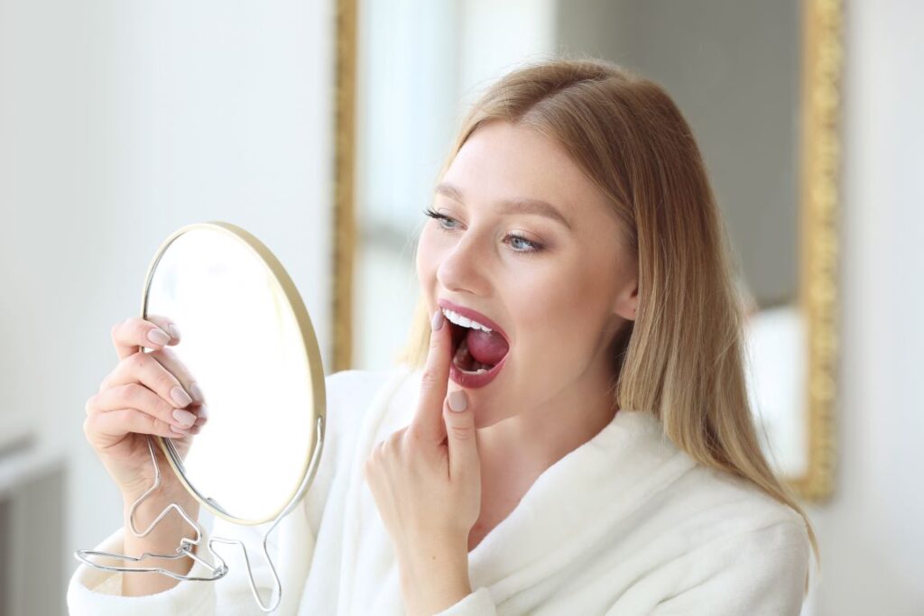 A woman examining her teeth in the mirror.