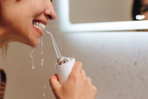 Profile view of a woman using a waterpik over the bathroom sink